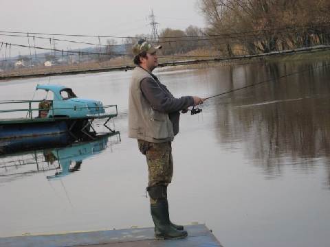 Артём ловит рыбу на спиннинг, стоя на пантоне